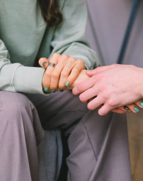 A therapist holds her client's hand.