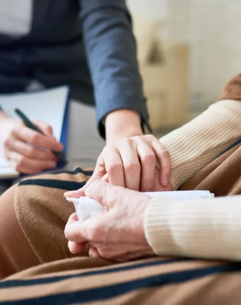 A therapist holds her client's hand.