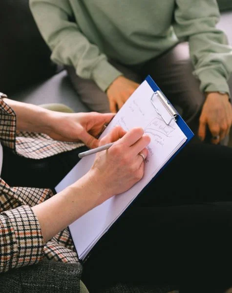 A therapist writes notes while sitting with her client.