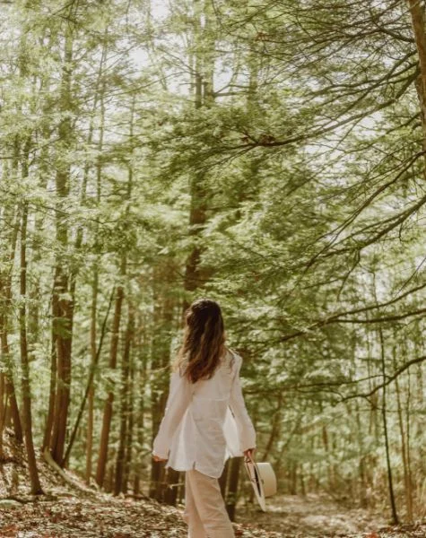 A woman walks through a forest.