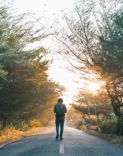 A man walks down the centre of a street.