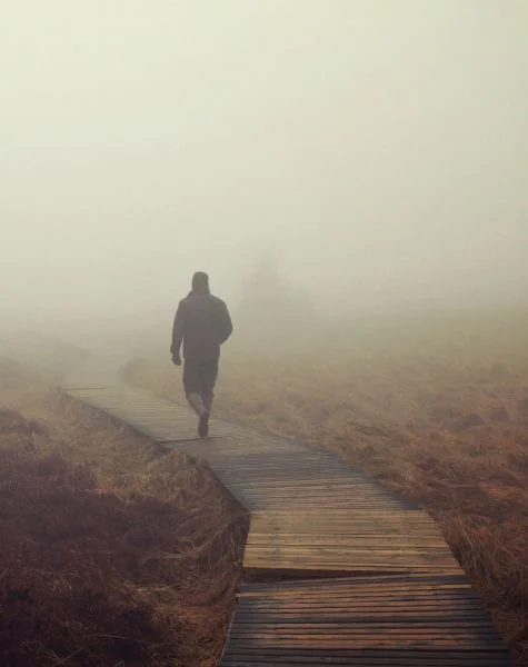 A man walks outside on a foggy day.