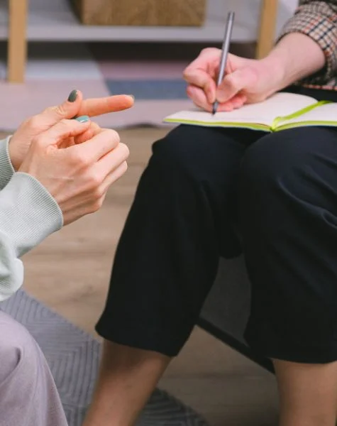 A therapist writes notes while sitting with her client.