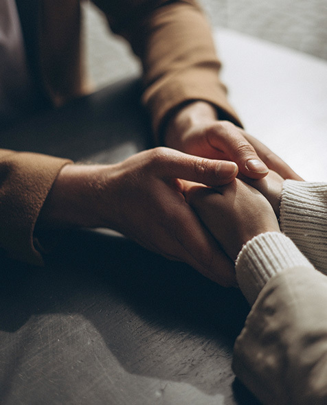 A therapist holds her client's hands.